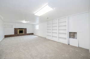 Basement featuring a fireplace, a textured ceiling, and carpet