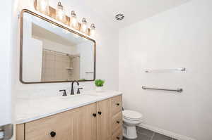 Bathroom with vanity, toilet, and tile patterned flooring