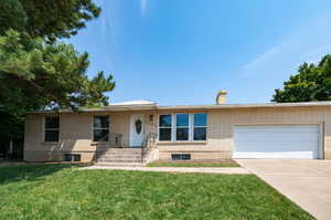 View of front of home with a front yard, cooling unit, and a garage