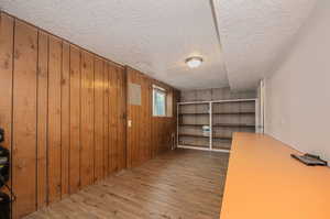 Interior space with a textured ceiling, wooden walls, and light hardwood / wood-style floors