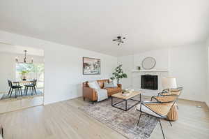 Living room featuring a notable chandelier, a high end fireplace, and light hardwood / wood-style floors