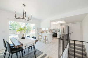 Tiled dining space featuring a notable chandelier and sink