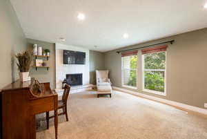 Interior space with carpet floors, a textured ceiling, and a brick fireplace