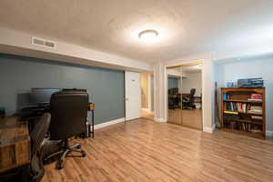 Office with a textured ceiling and light wood-type flooring