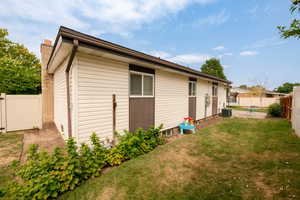 Rear view of property with a lawn and central AC