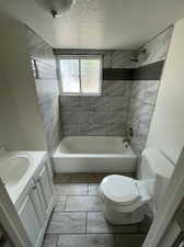 Full bathroom with tile patterned floors, vanity, tiled shower / bath combo, and toilet