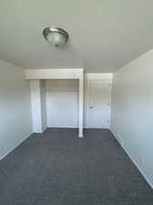 Unfurnished bedroom featuring dark colored carpet and a closet