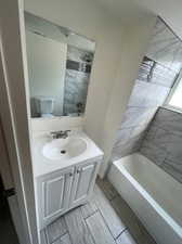 Full bathroom with toilet, tile patterned floors, vanity, and tiled shower / bath combo