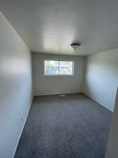 Empty room with a textured ceiling and carpet floors