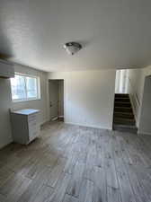 Unfurnished living room featuring a textured ceiling, light wood-type flooring, and a wall unit AC