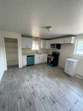 Kitchen featuring a textured ceiling, white cabinetry, light hardwood / wood-style floors, stainless steel appliances, and sink