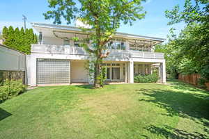 Back of house with a yard and a balcony