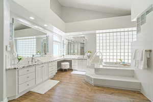 Bathroom with vanity, wood-type flooring, a healthy amount of sunlight, and a tub to relax in