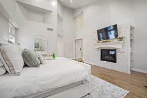 Bedroom with a fireplace, hardwood / wood-style flooring, and a high ceiling