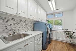 Clothes washing area featuring cabinets, separate washer and dryer, sink, and light hardwood / wood-style floors