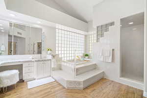 Bathroom featuring hardwood / wood-style floors, lofted ceiling, vanity, and separate shower and tub