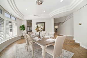 Dining space featuring light parquet floors, crown molding, a raised ceiling, and a chandelier