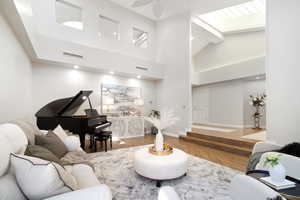 Living room with ceiling fan, high vaulted ceiling, and wood-type flooring