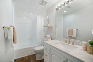 Full bathroom featuring hardwood / wood-style flooring, vanity, shower / tub combo, and toilet