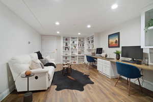 Home office featuring light hardwood / wood-style flooring, built in shelves, and built in desk