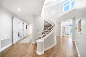 Corridor featuring a towering ceiling and light hardwood / wood-style flooring