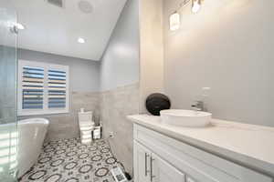 Bathroom with tile walls, tile patterned floors, and vanity