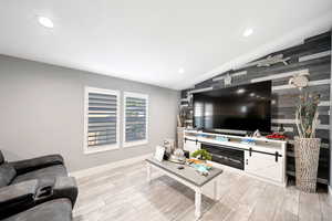 Living room with light hardwood / wood-style flooring, vaulted ceiling, and wooden walls