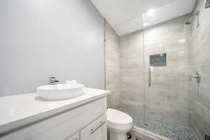 Bathroom featuring toilet, a tile shower, and vanity