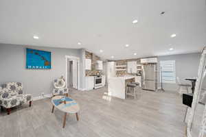 Living room with light wood-type flooring, sink, and vaulted ceiling