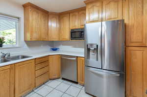 Kitchen with appliances with stainless steel finishes, sink, and light tile patterned floors