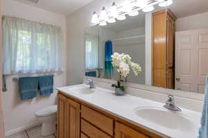 Bathroom with dual vanity, tile patterned floors, a textured ceiling, and toilet