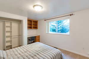 Carpeted bedroom featuring a textured ceiling and a closet