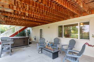 View of patio featuring a hot tub and a fire pit