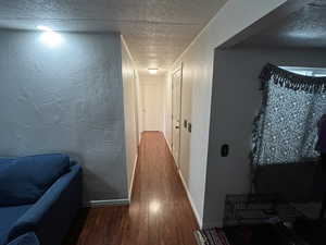 Hallway with hardwood / wood-style floors and a textured ceiling