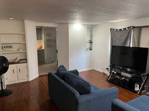 Living room with a textured ceiling, tile patterned floors, and built in features