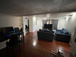 Living room featuring a textured ceiling, built in features, and hardwood / wood-style floors