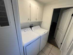 Laundry room with cabinets, light tile patterned floors, and separate washer and dryer