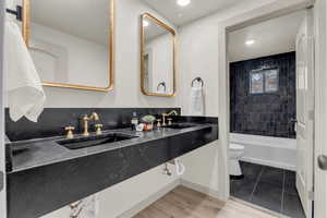 Bathroom with tile patterned floors, dual bowl vanity, and toilet