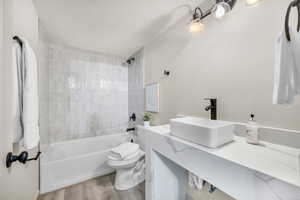 Full bathroom with tiled shower / bath, wood-type flooring, vanity, and toilet