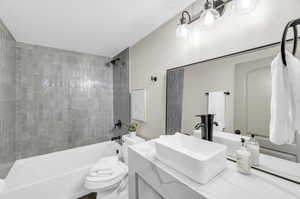 Full bathroom featuring tiled shower / bath combo, vanity, and toilet