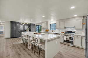 Kitchen with pendant lighting, appliances with stainless steel finishes, light stone countertops, light hardwood / wood-style flooring, and a kitchen island