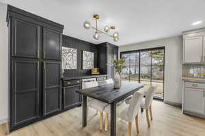 Kitchen featuring tasteful backsplash, light wood-type flooring, a notable chandelier, and pendant lighting