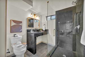 Bathroom featuring toilet, tile patterned floors, vanity, and an enclosed shower