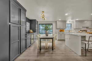 Kitchen featuring light stone counters, gray cabinets, tasteful backsplash, and light hardwood / wood-style floors