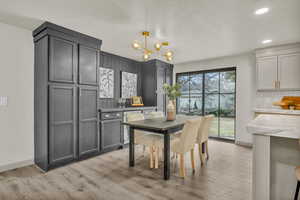 Kitchen with light hardwood / wood-style flooring, pendant lighting, a wealth of natural light, gray cabinets, and tasteful backsplash