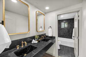 Full bathroom featuring double sink vanity, tile patterned floors, tiled shower / bath, and toilet