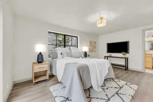 Bedroom with connected bathroom and light hardwood / wood-style floors