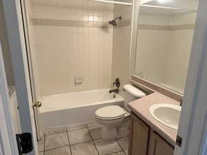 Full bathroom featuring tiled shower / bath, vanity, toilet, and tile patterned floors