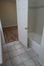 Bathroom with hardwood / wood-style flooring and tiled shower / bath