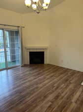 Unfurnished living room with an inviting chandelier, plenty of natural light, and wood-type flooring